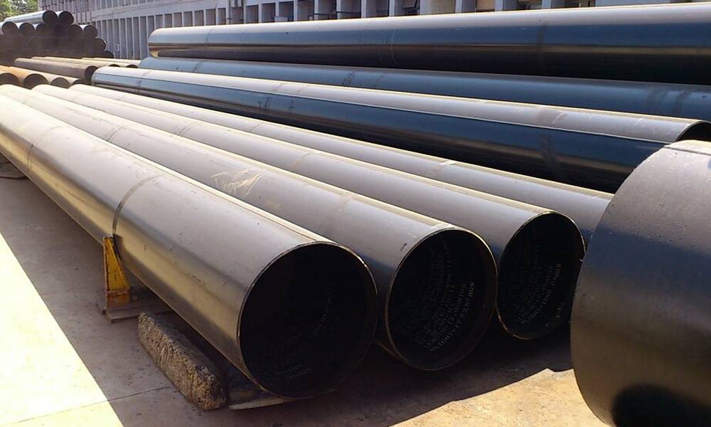 Large diameter steel pipes stacked in an outdoor yard.